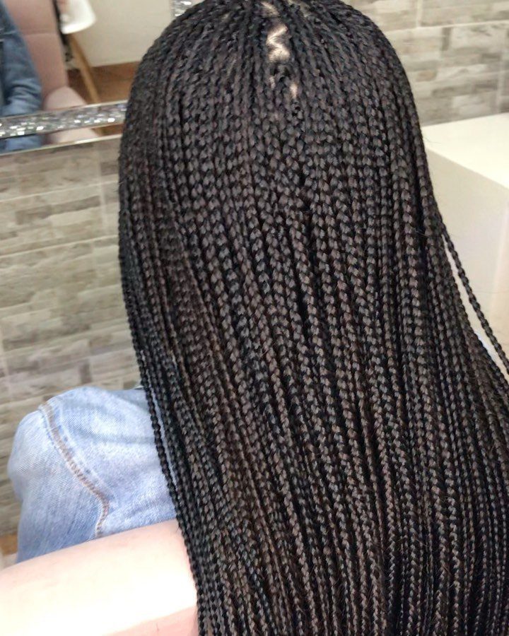 Long thin black braids cover the back of a person in a salon
