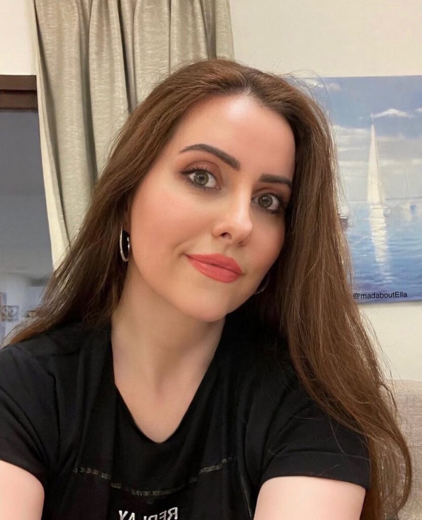 Woman with long warm medium brown hair posing in a black top