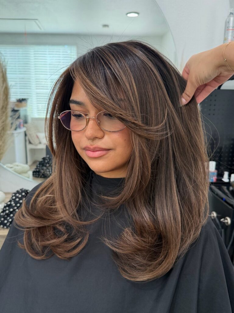 Chestnut-brown layered hair with subtle lighter face-framing pieces in a salon