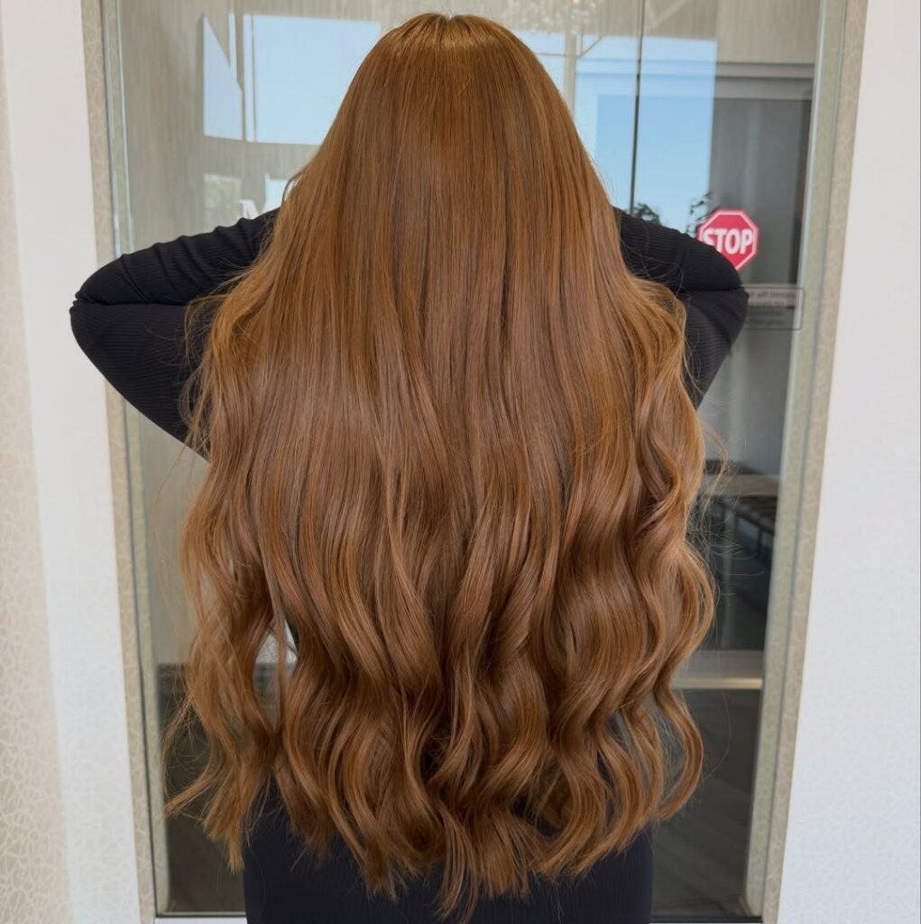 Long honey brown hair styled in loose waves from the back