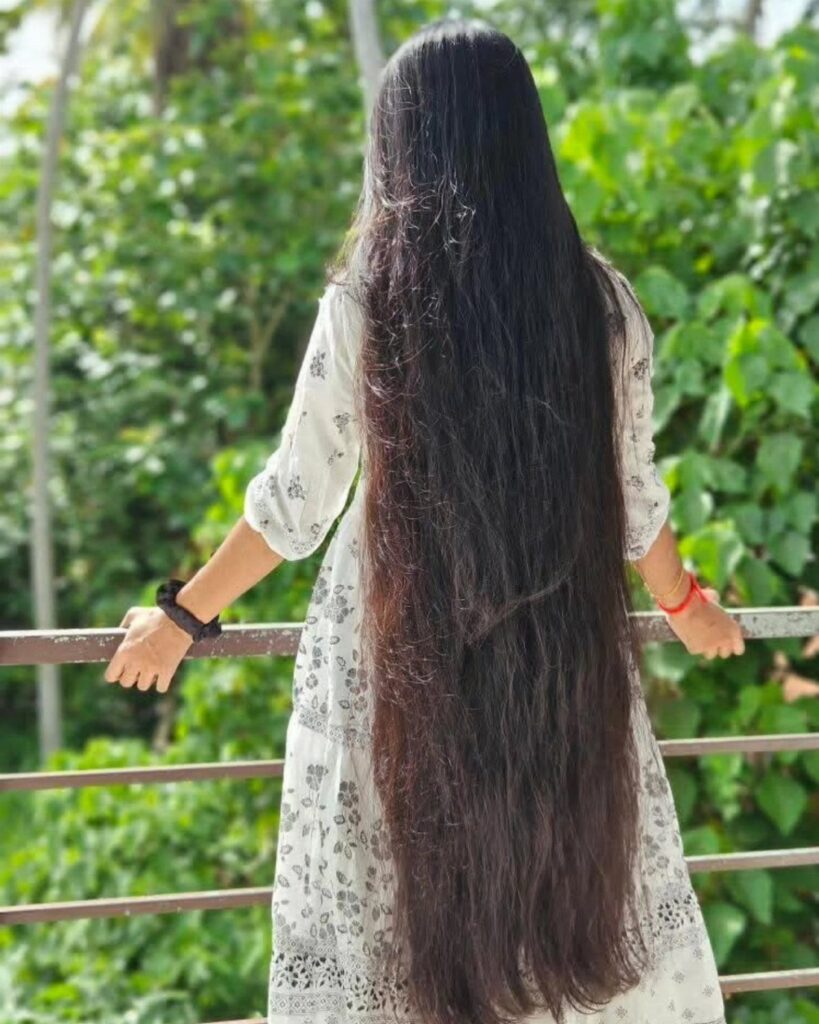 Very long black hair falls down a person’s back at an outdoor railing