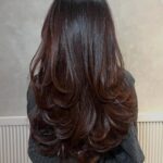 Long layered dark brown hair with cascading curled ends seen from behind