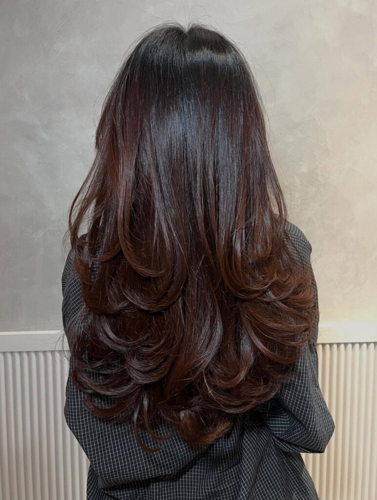 Long layered dark brown hair with cascading curled ends seen from behind