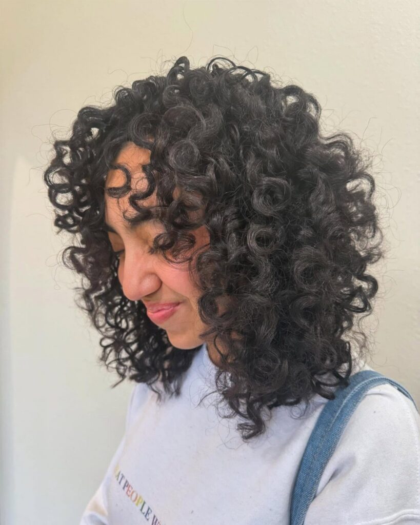 Woman with voluminous short layered dark curls framing her face and shoulders