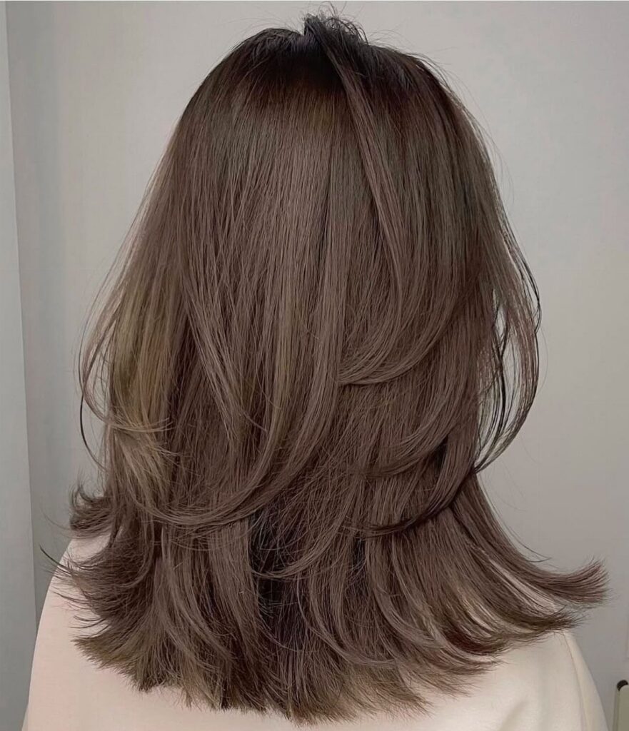 Shoulder-length layered brown haircut with feathered, sweeping ends